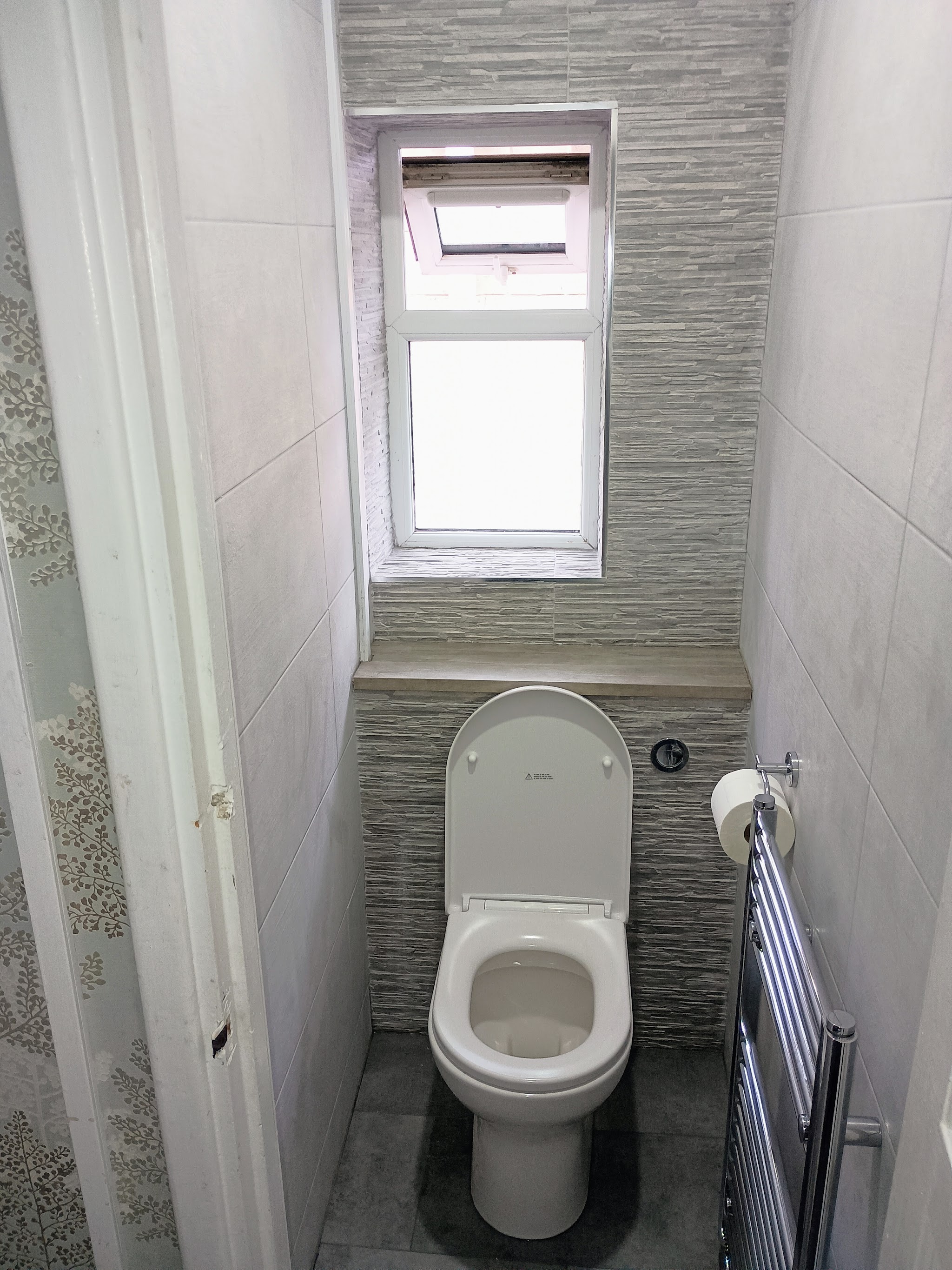 The separate toilet after the refit: tiled walls, new close-coupled toilet and chrome towel rail